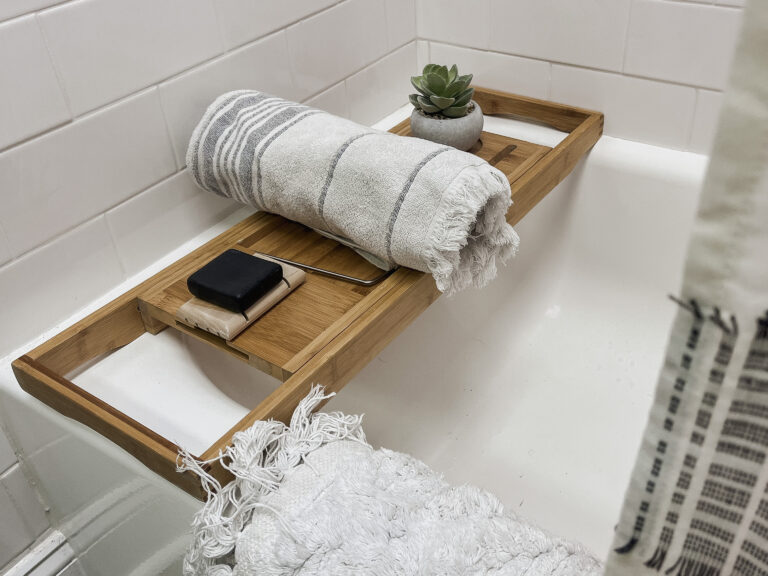 Bath tub tray with towel, succulent, and soap in shower