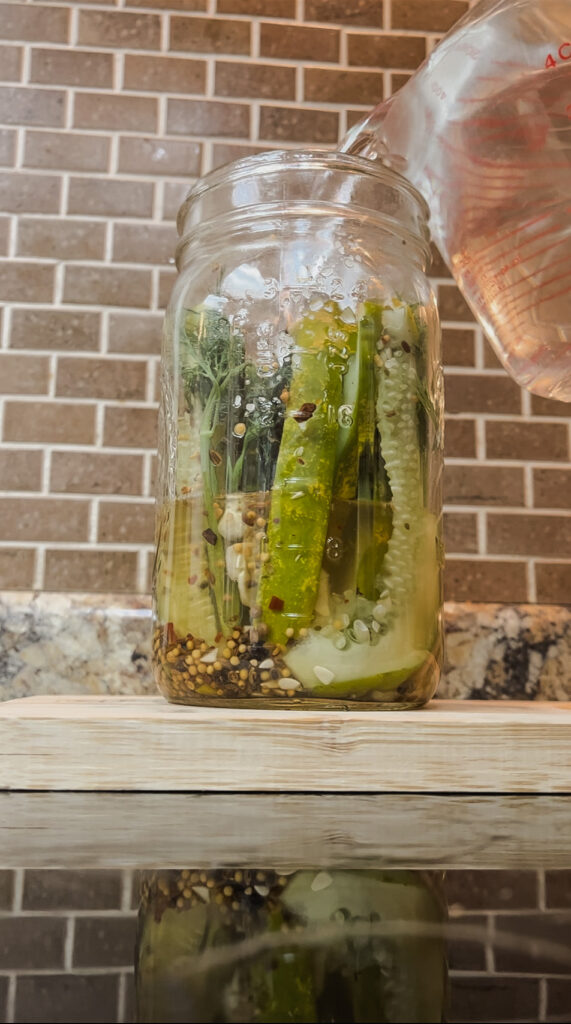 jar of pickles with brine pouring into the jar